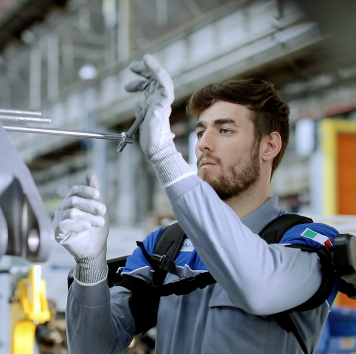 worker at a factory environment supported by an exoskeleton for arms and shoulders.